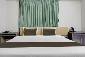 - une chambre avec un grand lit et un rideau vert dans l'établissement Hotel Seven Hills, à Dāpuri