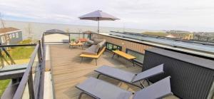 einen Balkon mit Stühlen, Tischen und einem Sonnenschirm in der Unterkunft Enkhuizer Strand Cube Elite Estel mit Dachterrasse und Zaun Haus Nr 337 in Enkhuizen