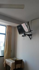 a television hanging from the ceiling of a room with a table at Casa del Huesped - Guest House in Pucallpa
