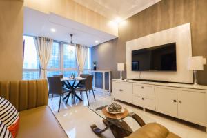 un soggiorno con grande TV e tavolo di Spacious 2BR Apartment in BGC with Workspace & Washer a Manila