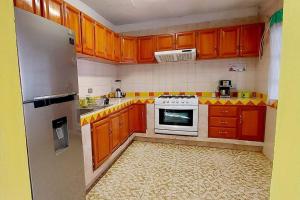a kitchen with wooden cabinets and a white stove at Casa Limón, es tu casa, tu grande residencia in Calvillo