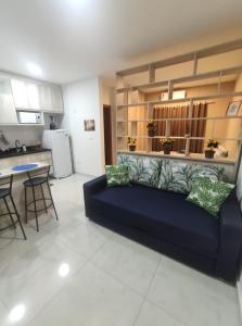 Flat Brilho do Sol في أوليمبيا: غرفة معيشة مع أريكة زرقاء ومطبخ