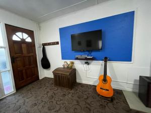 Pokój z telewizorem i gitarą na ścianie w obiekcie Casa w mieście Punta Arenas