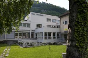 ein großes weißes Gebäude mit einem Berg im Hintergrund in der Unterkunft Hôtellerie Franciscaine in Saint-Maurice