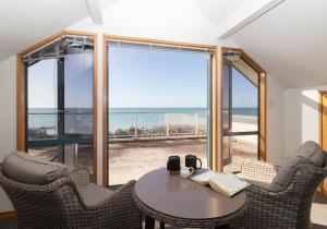 a room with a table and chairs with a view of the ocean at Beachfront Bliss On Wanaka Terrace Support Local in New Plymouth