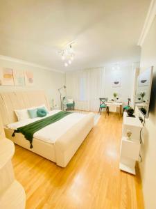 sypialnia z dużym białym łóżkiem i drewnianą podłogą w obiekcie Like Home Apartments w mieście Ałma-Ata