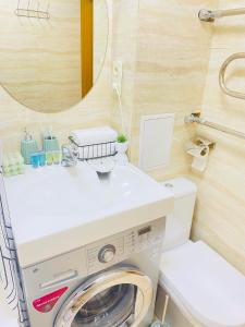 a bathroom with a washing machine and a mirror at Like Home Apartments in Almaty