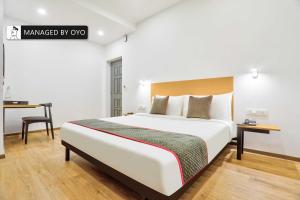 1 dormitorio con 1 cama grande y escritorio en Super Townhouse Imperial Stays Lawspet, en Pondicherry