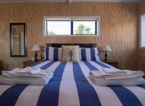 um quarto com uma cama grande com riscas azuis e brancas em The Boat House On Dixon em Oakura
