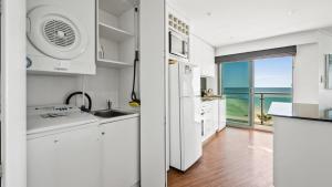 a kitchen with white appliances and a view of the ocean at Sea Side 411 in Mandurah
