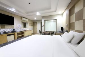 a hotel room with a large bed and a kitchen at Q5 Hotel Busan Songdo in Busan