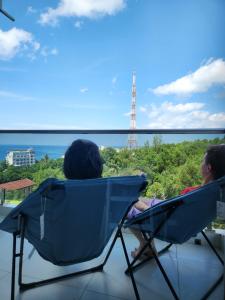 Dos personas sentadas en sillas mirando hacia el océano en Mi Amor Luxury Island Apartment - 3 minutes to the beach, en Phu Quoc