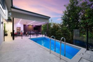 a house with a swimming pool and a patio at Cicada Close Hideaway in Buderim