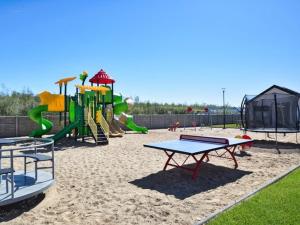 a playground with a slide and play equipment in the sand at Cozy holiday homes for 4 people, azy in Łazy