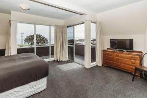 a bedroom with a bed and a flat screen tv at Blue Haven On Belt Waterfront in New Plymouth