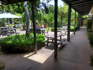 un patio con bancos, mesas y árboles en Coach House Inn, en Bright