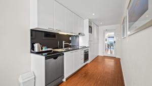 a kitchen with white cabinets and a wooden floor at Sea Side 508 in Mandurah