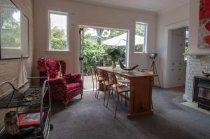 een woonkamer met een tafel en stoelen en een open haard bij Bungalow Eight in New Plymouth