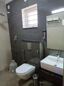 La salle de bains est pourvue de toilettes blanches et d'un lavabo. dans l'établissement Hotel Grand Villa, à Yelahanka