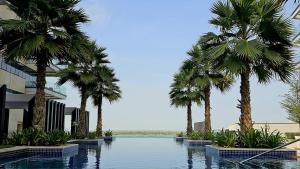 een zwembad met palmbomen voor een gebouw bij Voyage 2 Bedroom In Mayan With Ocean Views in Abu Dhabi