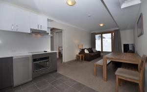 a kitchen and living room with a table and a couch at Smiggins Hotel & Chalet Apartments in Perisher Valley