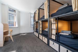 a room with bunk beds with a desk and a chair at Tequila Sunrise Hostel Adelaide in Adelaide