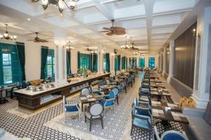a large dining room with tables and blue chairs at Vườn Vua Resort & Spa -by Bay Luxury in Ðồng Phú