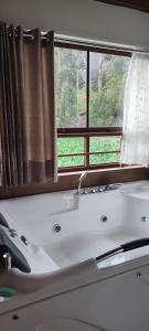 y baño con bañera y ventana. en Casa Arin valle sagrado de los inkas, en Cusco