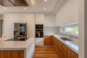 eine Küche mit weißen Wänden, Holzschränken und einem Waschbecken in der Unterkunft Luxurious 5 bedrooms and with pool in Fernão Ferro