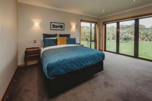 a bedroom with a bed with a blue comforter and windows at Serenity Lodge Getaway in Egmont Village