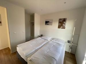 um quarto com 2 camas e lençóis brancos em Marina Strandbad Chalet Aan het Strand mit Zaun Haus Nr 133 em Olburgen