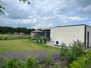 un pequeño edificio blanco con jardín en Marina Strandbad Chalet Aan het Strand mit Zaun Haus Nr 133, en Olburgen