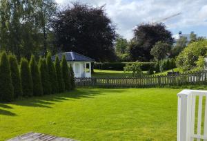 um quintal com uma cerca e uma casa branca em Førde sentrum - Lindbøen Gjesterom em Førde
