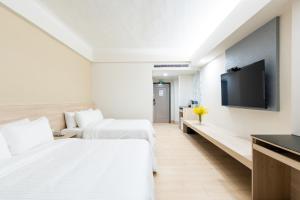 um quarto de hotel com duas camas e uma televisão de ecrã plano em Etung Hotel em Taichung