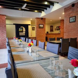 a long table in a restaurant with tables and chairs at Hotel Ananda Inn in Lumbini