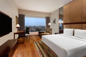 a hotel room with a large bed and a desk at Courtyard by Marriott Ahmedabad in Ahmedabad