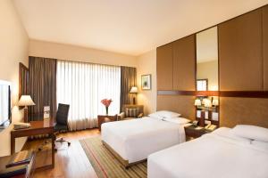 a hotel room with two beds and a desk at Courtyard by Marriott Ahmedabad in Ahmedabad