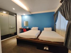 1 dormitorio con 2 camas y pared azul en Ryokan Chic Hotel en Petaling Jaya