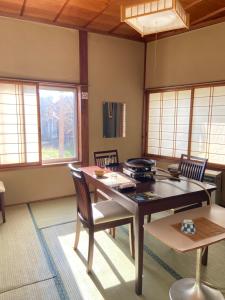 uma sala de jantar com mesa, cadeiras e janelas em Yoshidaya Ryokan em Zao Onsen