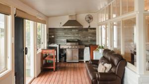 a living room with a leather couch and a kitchen at Riverfront Retreat - Sussex House Holiday Park in Sussex inlet