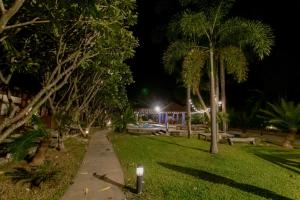 un parque nocturno con bancos y palmeras en Namsai Resort Kanchanaburi, en Kanchanaburi