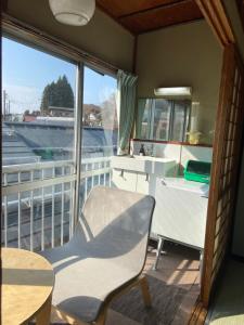 a room with a chair and a table and a balcony at Yoshidaya Ryokan in Zao Onsen