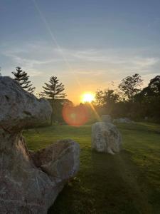 a sunset with two large rocks in a field at Athena Glamping Khaoyai in Pak Chong