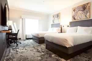 ein Hotelzimmer mit 2 Betten, einem Schreibtisch und einem Fenster in der Unterkunft Champions Club Texas in Houston
