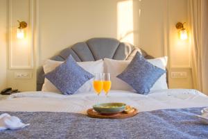 Dwie szklanki soku pomarańczowego i miskę na łóżku. w obiekcie Mademoiselle Boutique Resort and Cafe w mieście Vagator