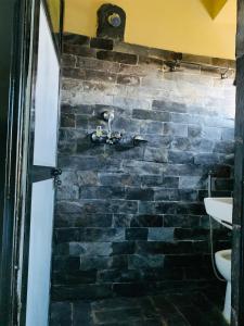 een badkamer met een stenen muur en een wastafel bij Bandipur Samira Homestay - Experience the Best for Less in Bandipur