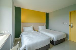 two beds in a room with green and yellow walls at พิลโล่ อินน์ พะเยา Pillow Inn Phayao in Phayao