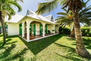 a house with palm trees in the yard at Villa à la Plage, lagon à 500m, climatisée in Saint-Paul