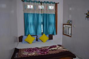 a room with a bed with blue curtains and a window at Hostel shivshakti khajuraho in Khajurāho