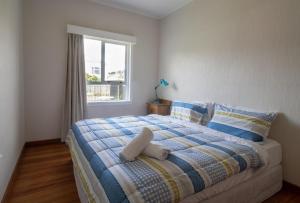 ein Schlafzimmer mit einem Bett mit einer Decke und einem Fenster in der Unterkunft Spacious In Strandon Great Value For A Family in New Plymouth